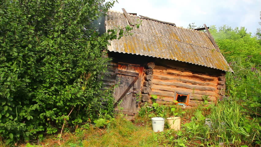 old obsolete russian bath-house in lush foliage