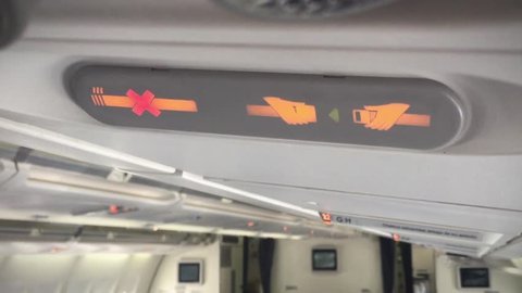 No Smoking and Fasten Seat Belt Sign in an Airplane. Close-Up. Zoom In. 