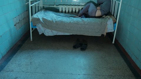 A patient in a psychiatric hospital. A sick man lying on the bed without moving