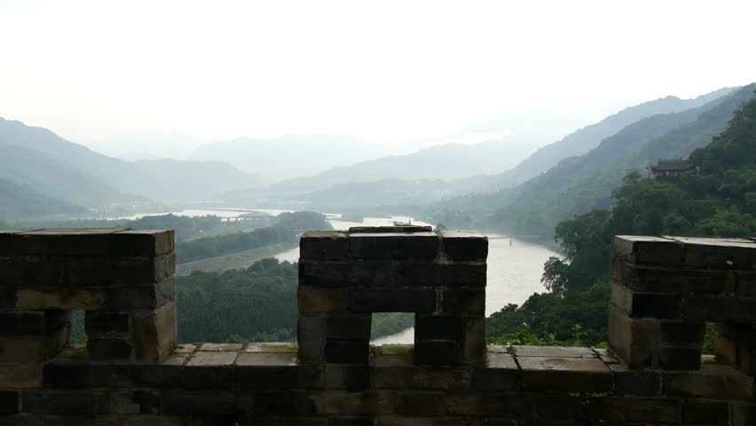Min river mountain skyline above stone wall fortification that feeds 2,000 year old Dijiangyan irrigation system, hot overcast summer day  - wide view