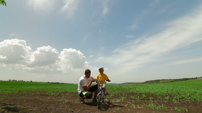 Happy Family Riding Bicycle. Father Helping Child Learn To Ride A Bike