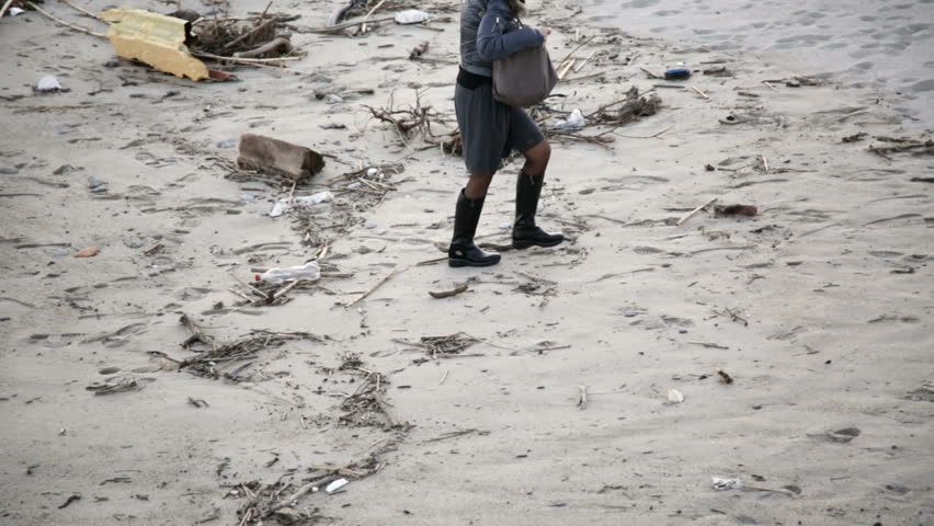 Lady is walking on the beach whit black boots.