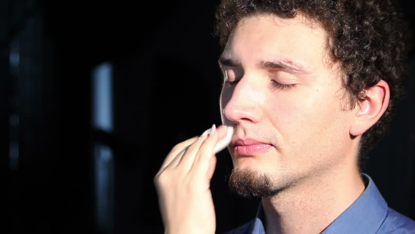 young man doing make-up - cleaning the face with a napkin