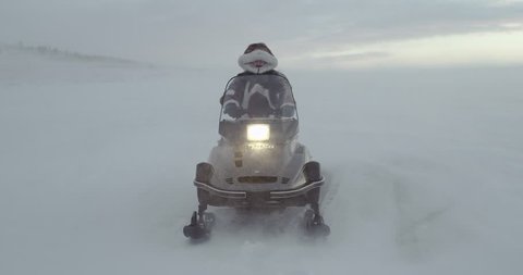 An adventurer  dressed in reindeer coat with fur hood looks away on a snowmobile at blizzard. Arctic expedition 2016. 4k shot , slow motion.  Stock Video