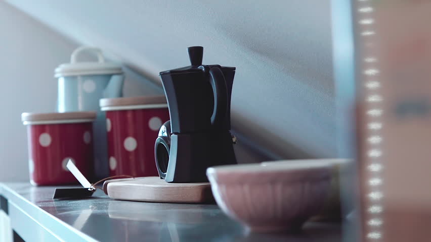 Young woman taking cafetiere from kitchen shelf