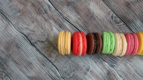 Colorful sweet macaroons on rustic wooden background, top view
