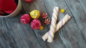 Candy, cupcakes and macaroons on a rustic wooden background, top view
