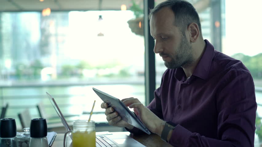 Young man using tablet computer and drinking cocktail in cafe
 | Shutterstock HD Video #22636930