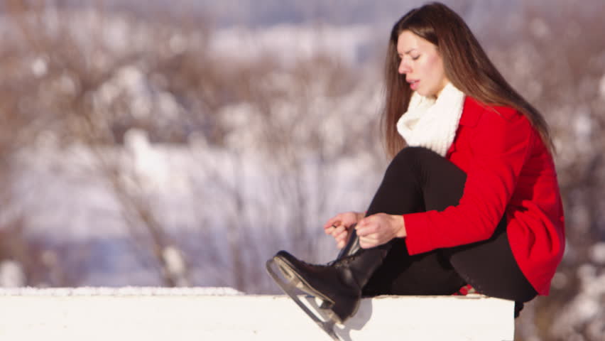 Slow motion young woman tying her ice skates
