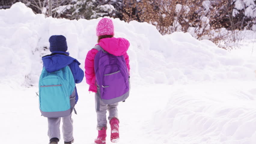 Two young children walking to school in the snow