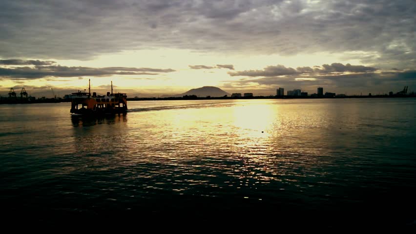A beautiful view of sunset and a ferry passing by. 
