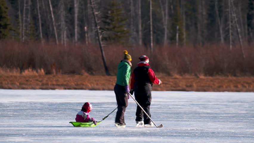 Moms and kids ice skating and playing hockey on a pond in the Canadian Rocky Mountains.  Vermilion Lake in Banff National Park, Alberta Canada.