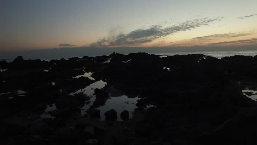 fire sunrise on the sea beach, rocky shore, high altitude aerial shot with motion