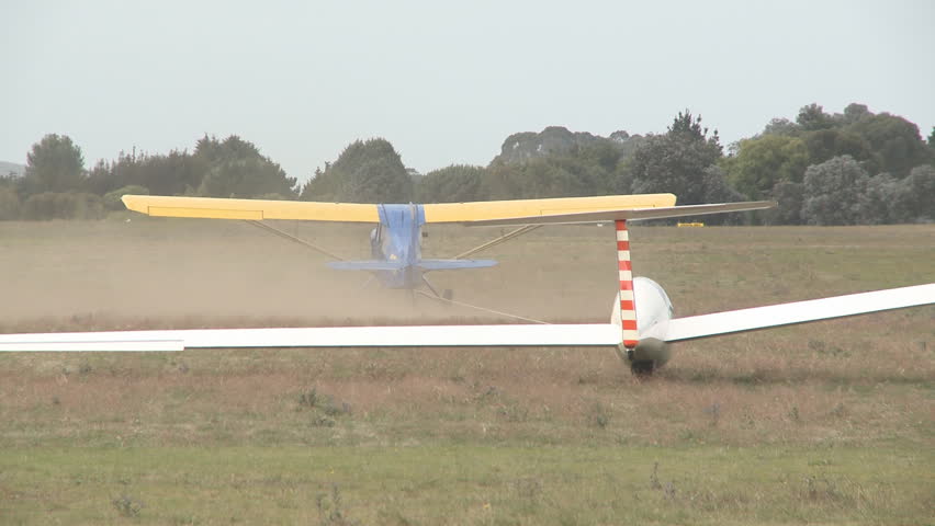 A glider lands on a grass runway 