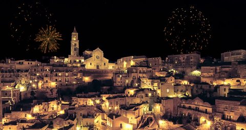 panoramic view of typical stones (Sassi di Matera) and church of Matera at night, with golden abstract blinking sparkle celebration fireworks light, happy new year holiday
