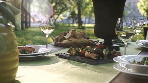 Catering. exquisitely decorated table with delicious meat, salads and wine for Romantic dinner in the forest. outdoor. sunny. picnic. slide.