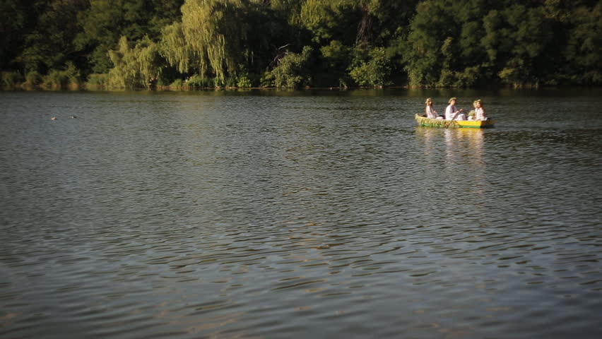 three girls and a guy in the Slavic national dress floating in a boat. Girls in wreaths in a boat. national tradition. embroidery.