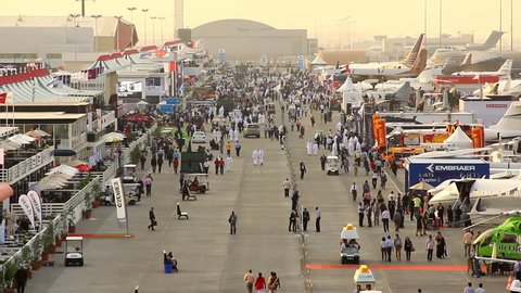 DUBAI, UAE - NOVEMBER 20, 2013: Dubai Air Show static exposition, general view, crowded trade exhibition area, Al Maktoum airport outdoors, many aircraft set to display. Visitors walk around busy area