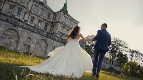 Wedding couple runing on sunset before old castle