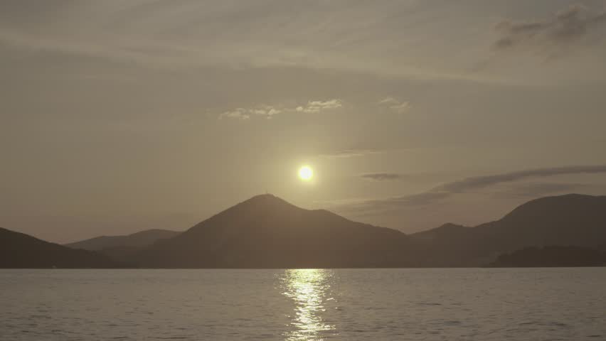 The sun sets behind the mountains on the sea shore . The Landscape Of Montenegro. Budva