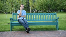 Teenager sitting on the banch in a park talking the mobile phone