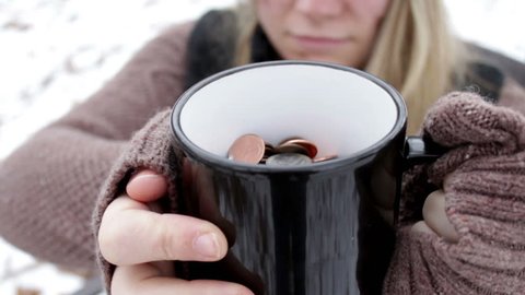 Homeless Woman shakes cup full of change at camera
