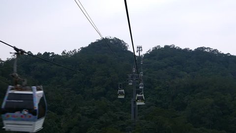Middle way of Maokong gondola lift, aerial view from move cabin, at dusk. Hanging line perspective, moving cabins and dark forest on mountain slope and ravine. Slowly slide down, approach mountainside