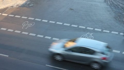 Street scene with bicycle lane, seen from above with with a car and a cyclists passing by. 