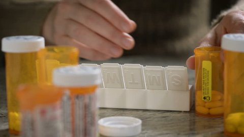 Prescription Medication - Female puts prescription pills into a pill container.