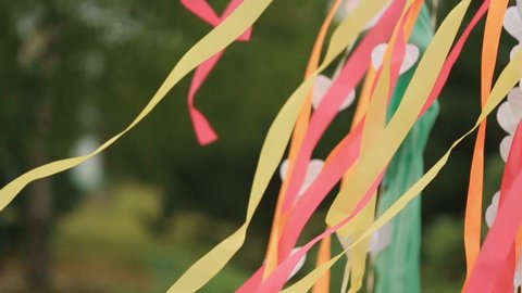 Wind blows colorful ribbons and paper hearts hanging from wedding altar
