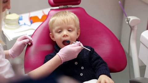 Child patient sitting on dental chair in paediatric dentists office. 