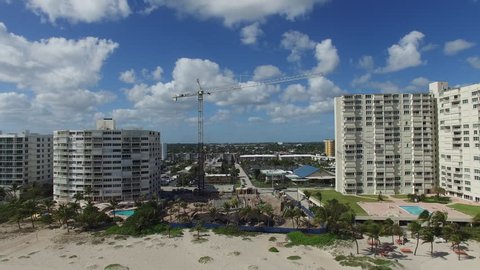 Fly over Atlantic ocean to beach front construction in South Florida. Referencing building near ocean during sea level rise.