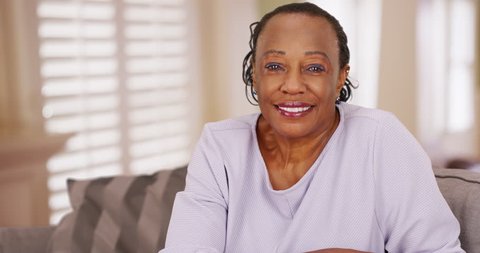 An older black woman happily looks at the camera. An elderly African American woman cheerfully poses for a portrait. 4k