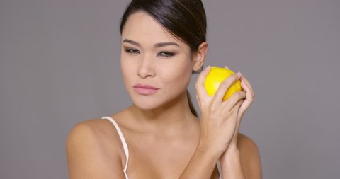 Cute young woman holding a halved fresh orange