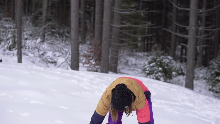 Winter landscape beautiful snowfall happy woman playing with falling snow. Young girl having fun playfully throwing snow playing outside with arms up in the air playful in wintertime.