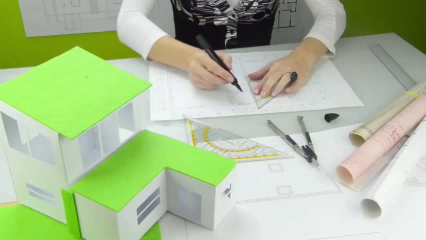 Woman architect at work. 
Architect at work drawing a plan for a new house. A model of the house in the forefront, plans on the table. Classical architect. Eco home. Royalty-Free Stock Footage #22780555