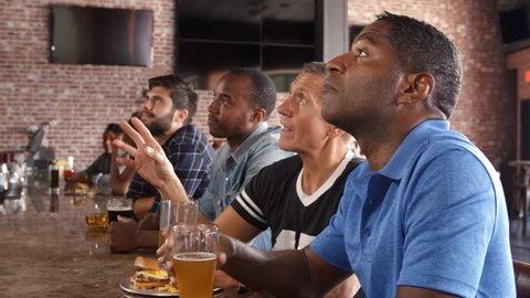Group Of Male Friends Watching Game In Sports Bar 