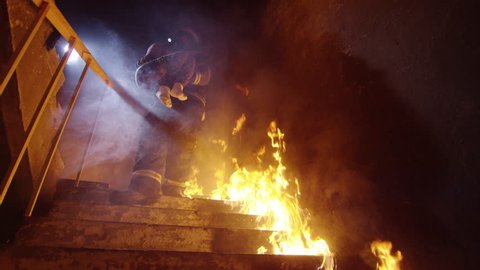 Brave Fireman Descends Burning Stairs with Saved Little Girl in His Hands. Open Flames are Seen Everywhere. Shot on RED Cinema Camera in 4K (UHD).