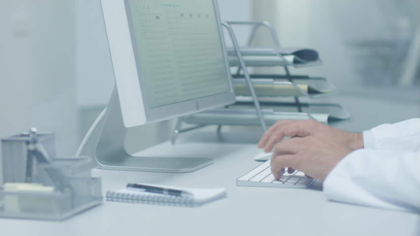 Close-up of Medical Practitioner's Hands Typing on a Keyboard Working on His Desktop Computer. In Background Assistant is Working. Shot on RED Cinema Camera in 4K (UHD). | Shutterstock HD Video #22782571