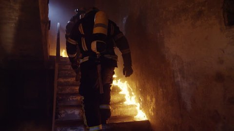 Two Brave Firefighters Go Up Burning Stairs. They Go Through Open Doors. Building is on Fire. Open Flames and Smoke Everywhere. Slow Motion.  Shot on RED EPIC 4K (UHD).