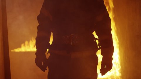Portrait Shot of A Brave Fireman Standing in a Burning Building Fire Raging Behind Him. Open Flames and Smoke in the Background. Shot on RED EPIC 4K (UHD).