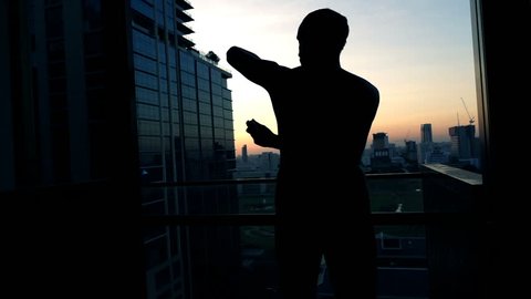 Silhouette of man applying anti-perspirant on armpit on terrace, super slow motion 240fps
