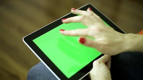 A woman holds a tablet computer with a green screen. Tablet computer with a green screen for your content. Woman with a tablet.
