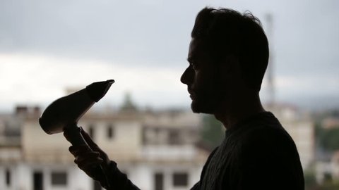 Cinemagraph. Seamless loop video. Silhouette of a man is drying his hair with the electric hairdryer. Video stock