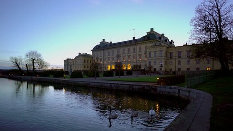 Drottningholm Palace outside of Stockholm at dusk. Swans passing in the foreground.