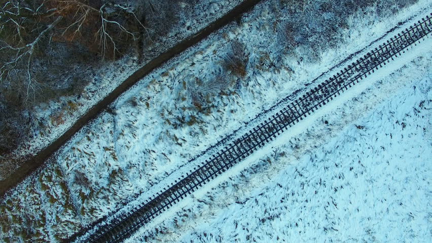 Aerial Of Railway In Snowy Winter Next To Lake And Trees