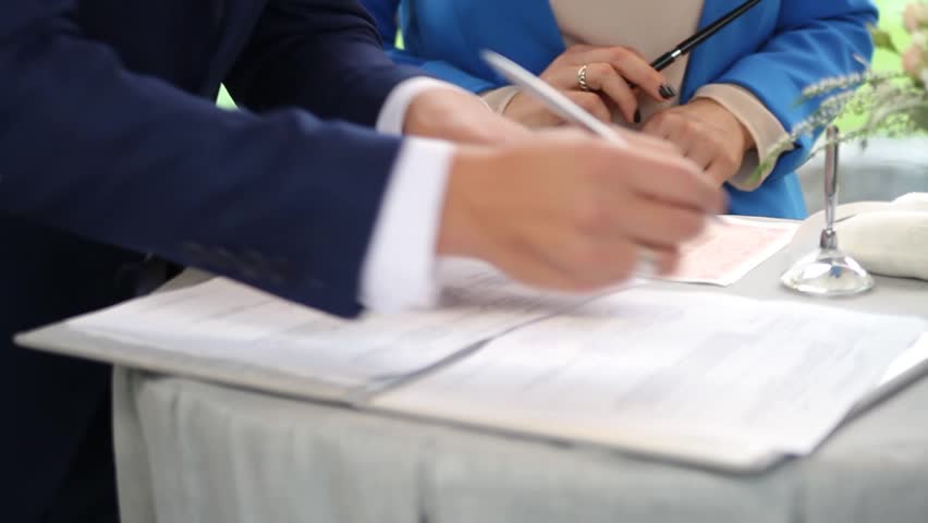 The groom signs the marriage registration documents. Young couple signing wedding documents. Man signs the documents Royalty-Free Stock Footage #22821622