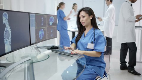4K Medical team in modern clinic looking at patient scans on computer screens Dec 2016-UK