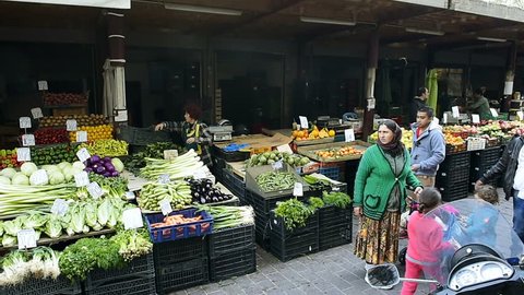 ATHENS, GREECE - CIRCA 2016: Panning over romantic market with customers buy choosing fresh vegetables olives tomatoes and organic vegetables and fruits at the Athens Central Market best food in town 