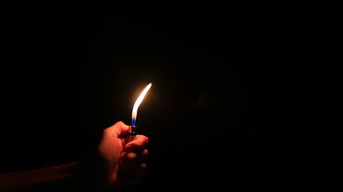 the big flame glowing on the lighter , on black background 